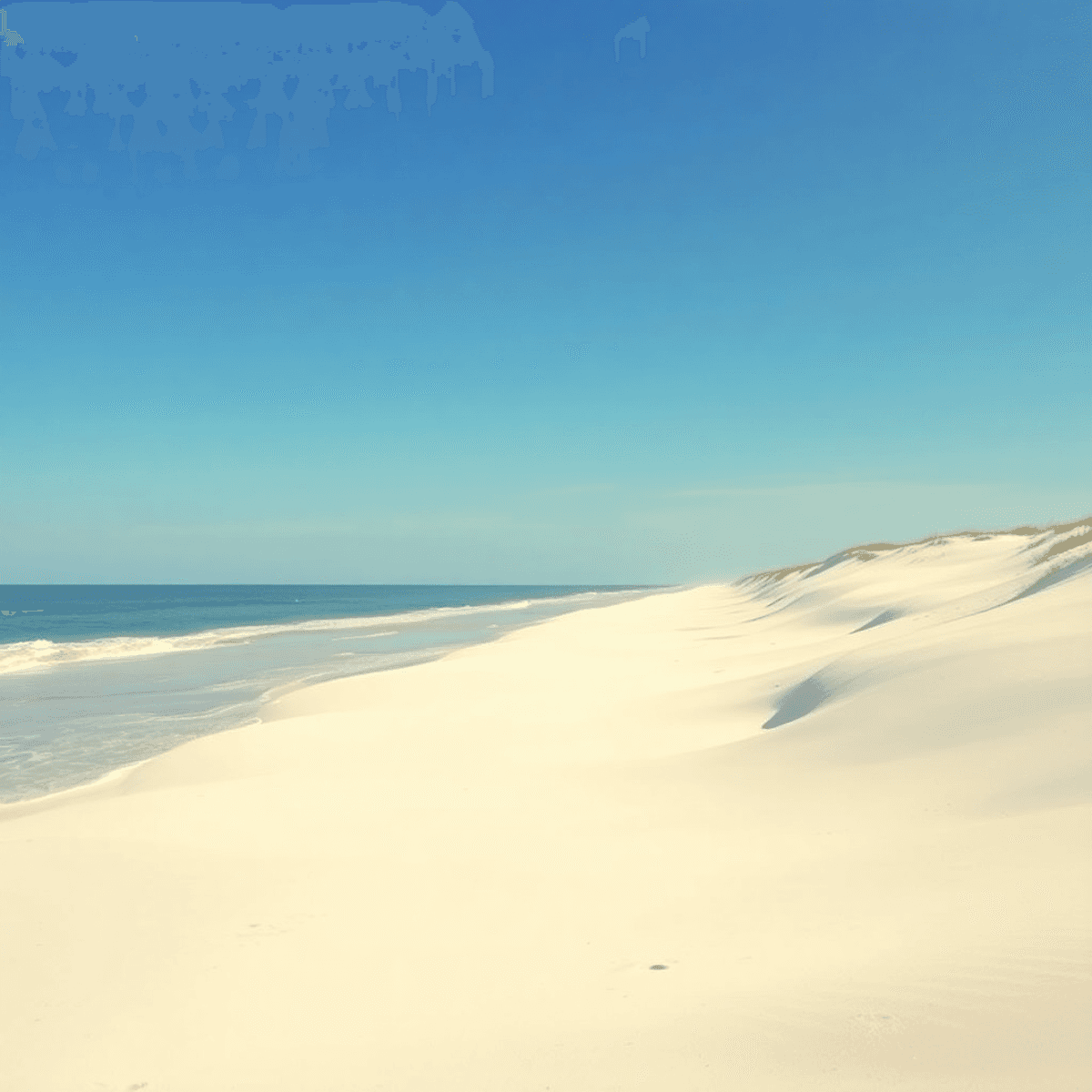 A tranquil beach scene at Butler Beach, Florida, featuring white sand, gentle waves, soft dunes, and romantic alcoves under a bright blue sky.